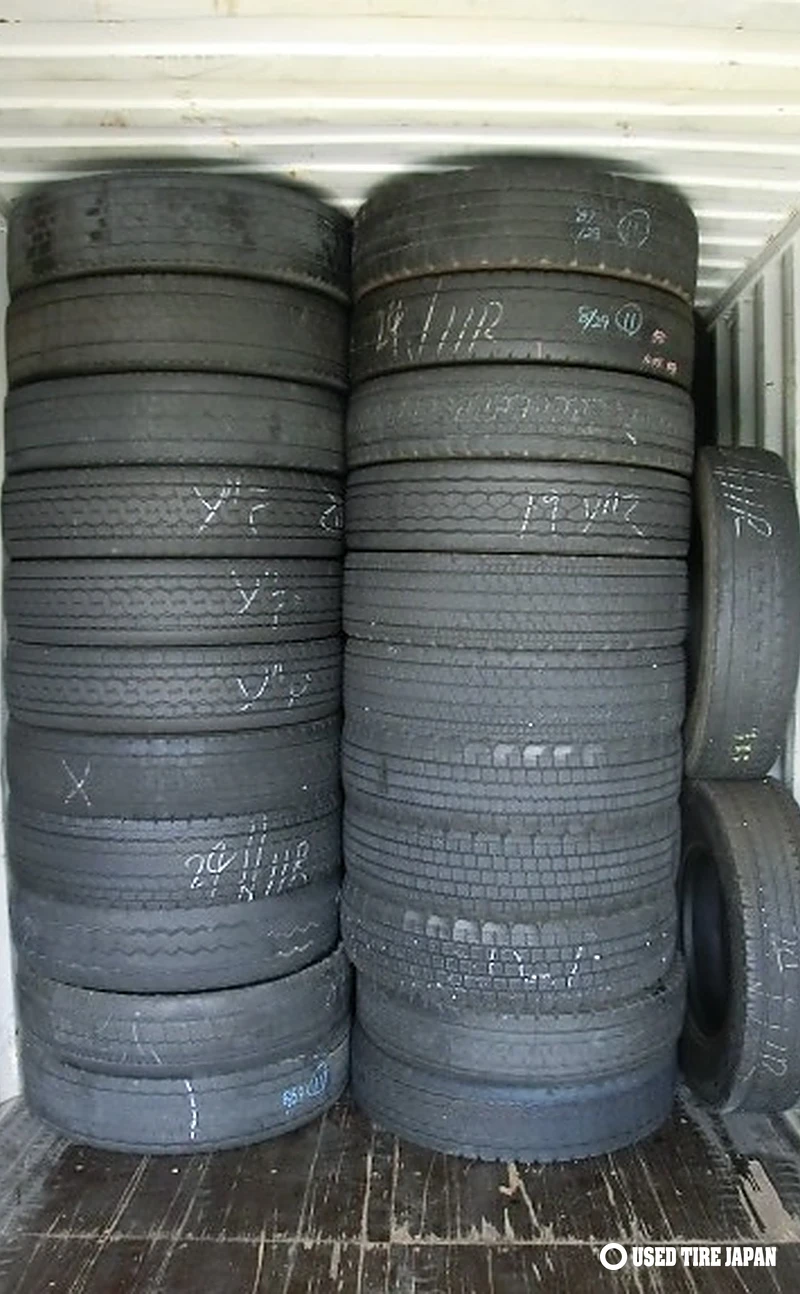 Used 11R22.5 truck tires stacked in a container before export, marked '11R' on the sidewall